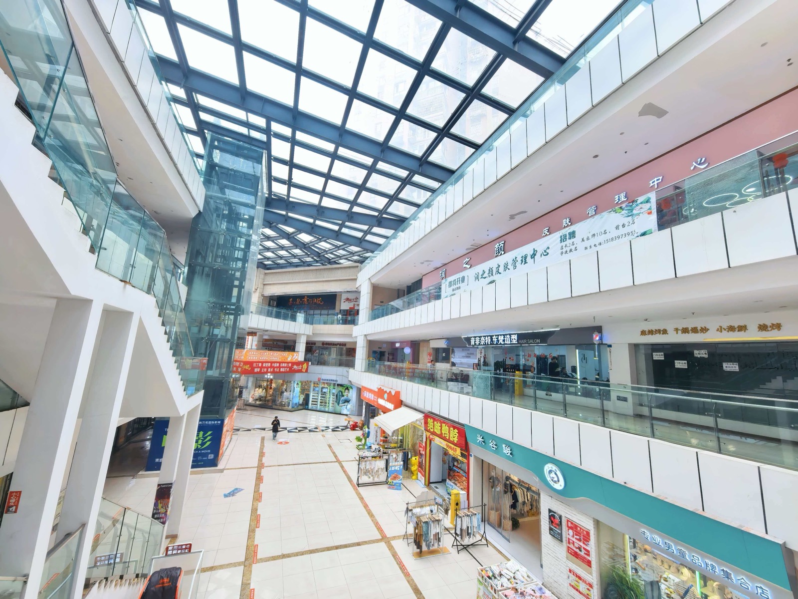 星都会商业内部中庭现状，采光顶、扶梯、中庭铺位和少量经营店铺可见