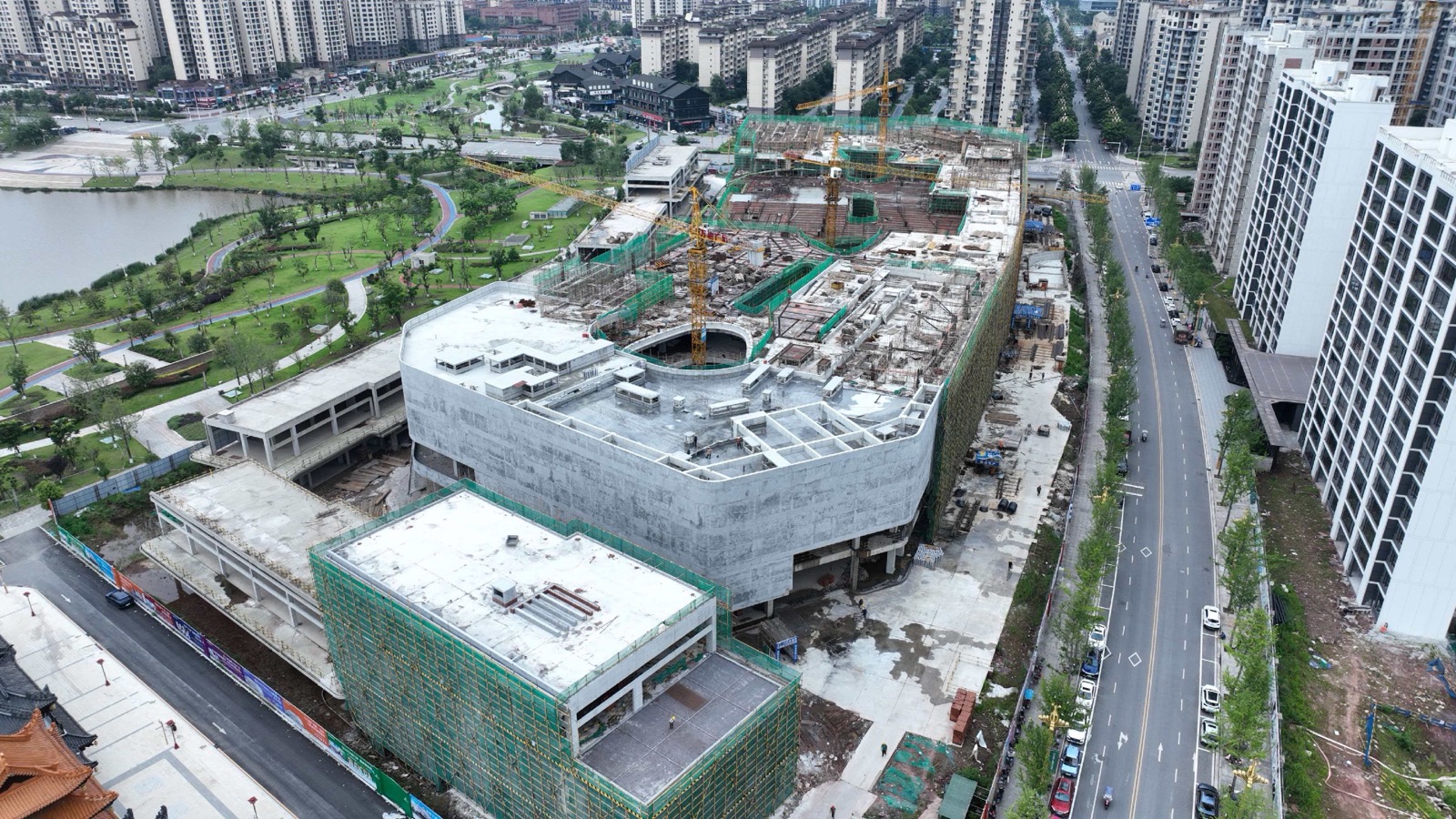 岳池万达广场工地近景，中央盒子、道路、塔吊和周边住宅清晰可见